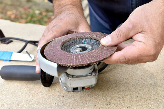 Top view. A man is mounting an abrasive flap disc onto an angle grinder.