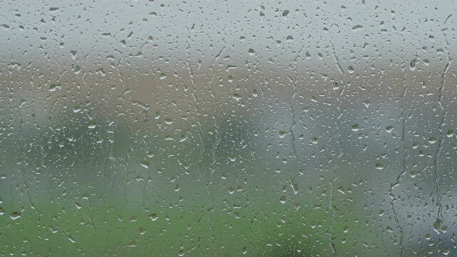 Rain drop hitting window glass and sliding down