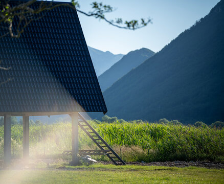 Atmospheric wooden cabin on stilts with stairs in foggy mountains.