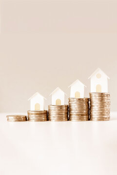 Stacked coins with house models symbolize real estate growth