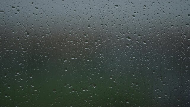 Rain drop hitting window glass and sliding down