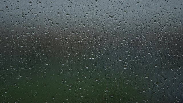 Rain drop hitting window glass and sliding down