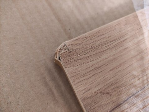 Close up of damaged chipboard corner with chipped edge and wood pattern on cardboard