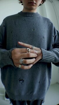 Closeup of hands with silver rings crossed over grey knit sweater