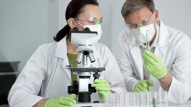 Scientists working in a modern research laboratory, collaborating on an experiment, analyzing samples with a microscope, performing biotechnology and medical science testing