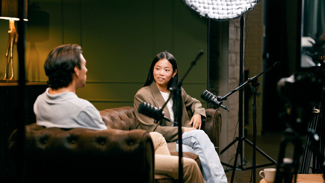 Content creators recording a podcast, discussing topics with microphones in a professional studio setup with lighting equipment
