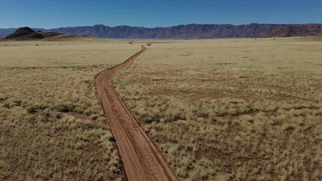 A drone flies over a narrow, deserted road and the dusty savanna in Namibia (Africa)