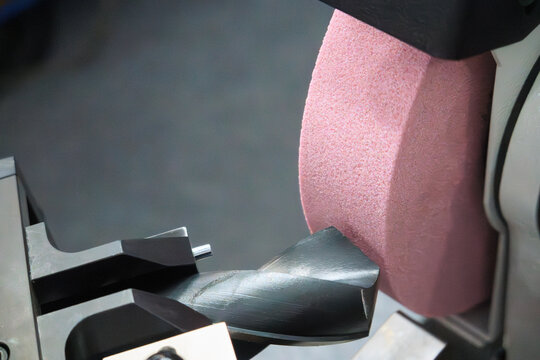 Close up of a drill tool regrinding process by an abrasive stone wheel