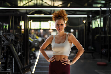 Naklejka premium Young fit woman standing in modern gym posing after workout
