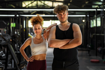 Naklejka premium Young man and woman posing for fitness motivation at gym