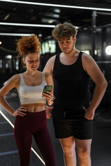 Naklejka premium Young couple using smartphone in modern gym