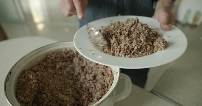 Close-up male hand put buckwheat on plate dish. 4K 10-bit