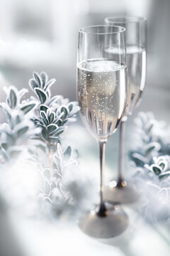 Two glasses of champagne with frozen branches in a snowy winter landscape. Vertical background for christmas and new year greetings.