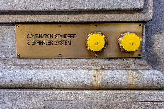 Yellow fire connection caps on a brass standpipe wall sign