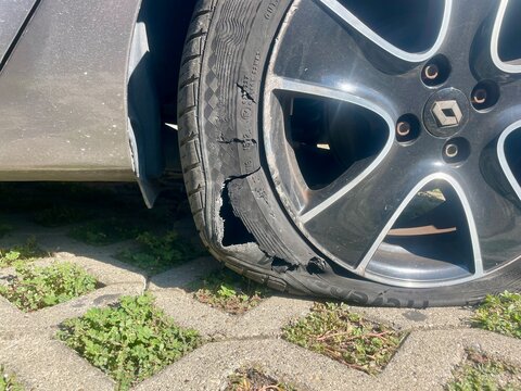 Bologna, Italy - 10.05.2026: Flat tire. Close up of a severely damaged car tire with a large blowout on a paved outdoor parking surface