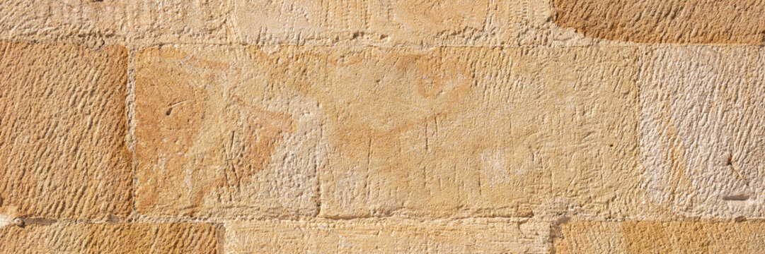 Natural sandstone block wall with chiseled stone surface texture. Mineral graining and masonry lines