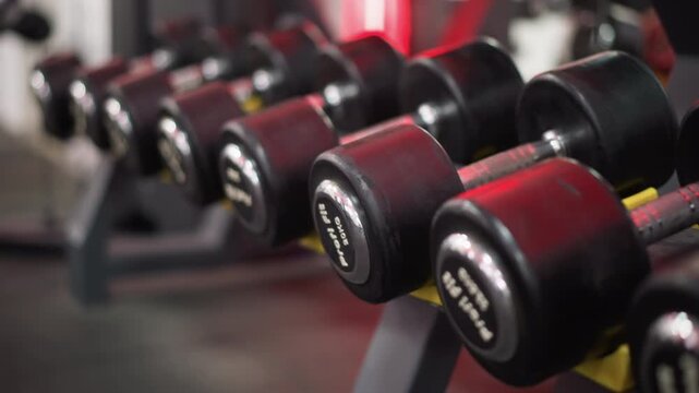 Close up on several red weight plates arranged neatly. focus remains sharp across row of weights with blurred gym background highlighting fitness tools in exercise environment