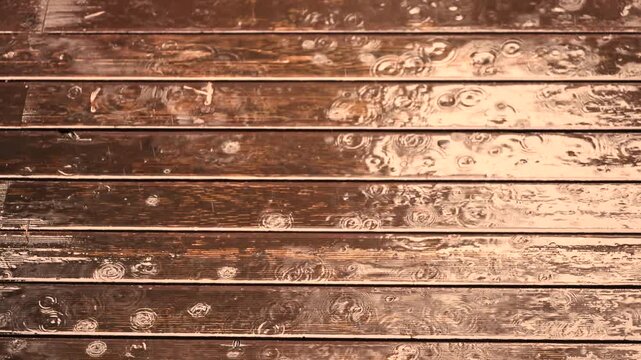 Heavy rain splatters onto straight wooden planks forming overlapping circles