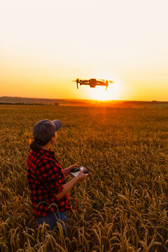 Woman farmer with drone on a wheat field. Smart farming and precision agriculture.