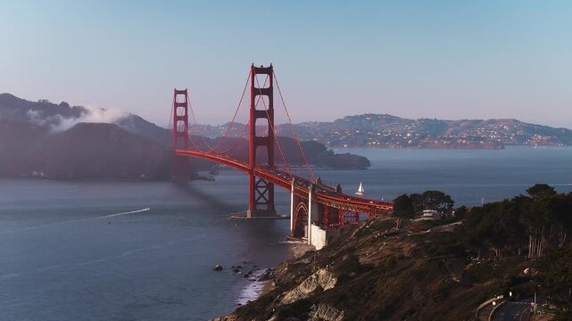 Aerial view captures the Golden Gate Bridge spanning across the bay toward Marin Headlands along the coastal bluffs of San Francisco, California, on a clear day.