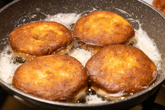Golden brown doughnuts frying in hot oil pan for traditional Fat Thursday celebration homemade sweet pastry dessert cooking process and delicious culinary snack background.	