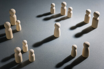 Obraz na płótnie Canvas A lone wooden figure surrounded by groups of people, representing loneliness in a crowd, social disconnection, isolation and lack of meaningful human connection despite being around others