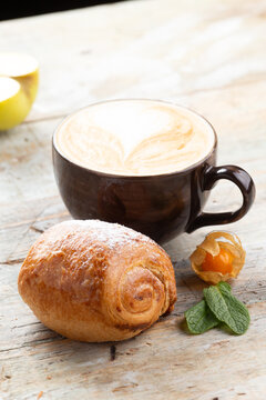 Latte coffee cup with pastry and physalis on wooden table breakfast