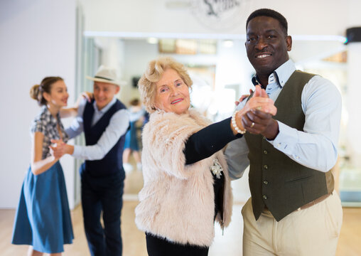 Man and senior woman dancing waltz in studio