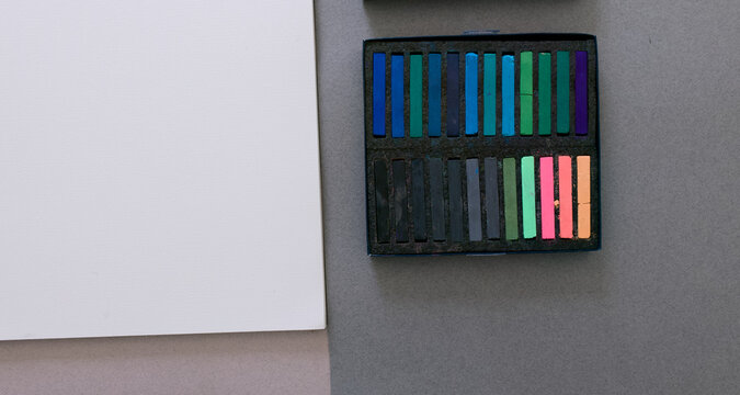Close up of colorful soft pastel chalks box next to blank paper mockup.