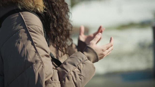 Shows back of woman with curly hair walking outside. Her arms move naturally by her sides in sync with each step along outdoor path. background is softly blurred emphasizing movement
