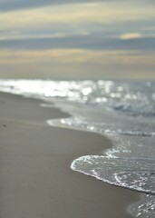 Sandy coastline and waves by the Baltic Sea. © elabracho
