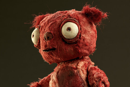 horror meat doll with ragged red ears, oversized pale eyes and stitched chest, side portrait, photorealistic