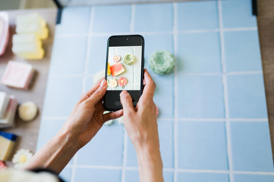 Closeup of a woman using smartphone taking content image of handmade soap for small business marketing and social media