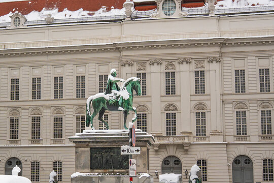 Vienna, Austria - circa Feb 2026: Equestrian statue of Emperor Joseph II at Josefsplatz in Vienna with snow on the green bronze, baroque facade of the Austrian National Library behind on a winter day