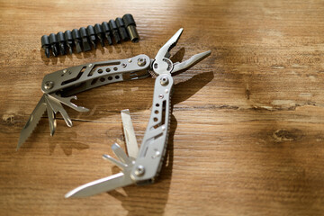 Multitool with blades and bit holder on wooden surface