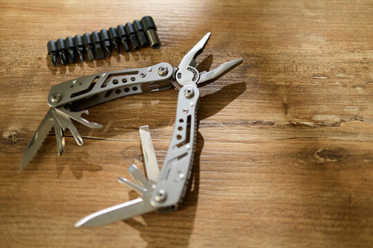Multitool with blades and bit holder on wooden surface