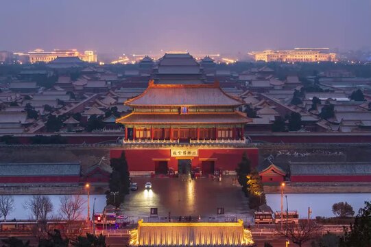 The Forbidden City in Beijing at dusk, illuminated traditional Chinese palace architecture with moat and city skyline in background