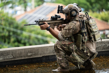 Fototapeta premium A soldier kneels on a rooftop holding a rifle, conveying a sense of vigilance and tactical readiness during a security patrol in an urban environment.