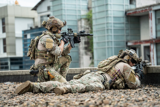 A team takes defensive positions on a rooftop during a tactical exercise, conveying focus and determination in an urban environment with modern buildings.