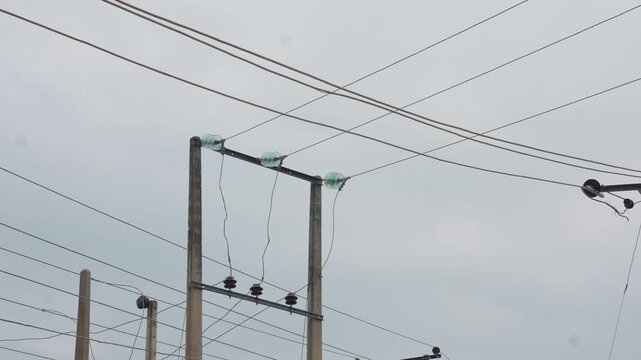 Continuous view of utility poles and overhead power lines against overcast sky showing static electrical transmission equipment in cloudy environment line
