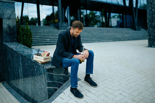 Unemployment despair forces dismissed male worker to hold beer bottle on corporate stairs.