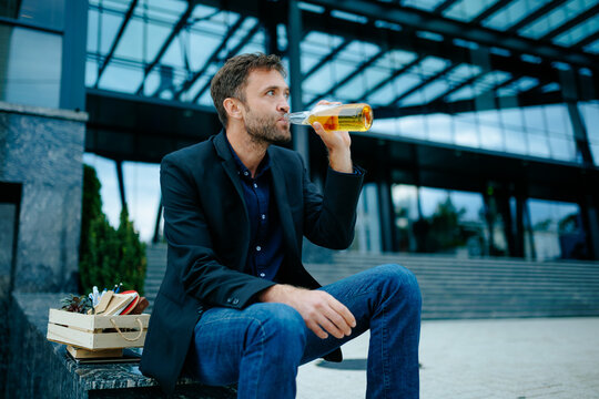 Lost work despair causes hopeless businessman to hold beer on outdoor stairs facing severe debt.