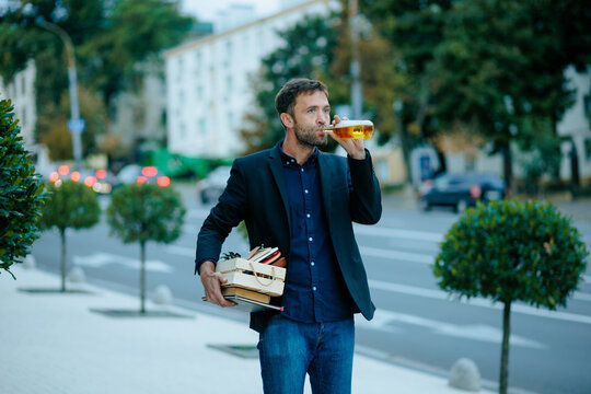 Lost job sorrow leaves confused dismissed employee walking on city sidewalk with carton box.