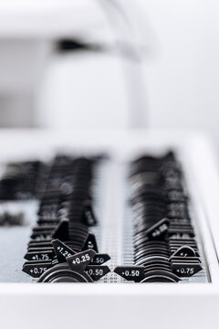 Close-up of optometry trial lens set with different diopters used for eye examination, refraction testing and eyeglass prescription.
