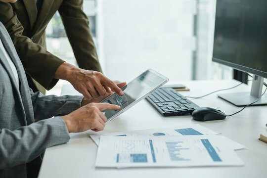 Business colleagues analyzing financial data on a tablet in an office setting