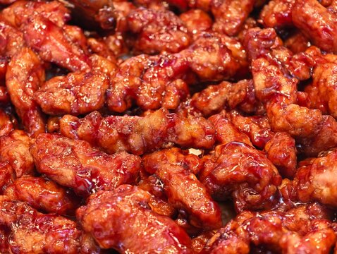 Close-up sweet and sour pork loin coated in glossy red sauce