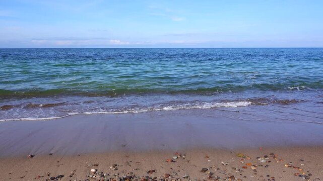 4k static video of a beautiful sandy beach with small ocean waves crashing on the shore, 1-minute seamless loop, with authentic sea sounds