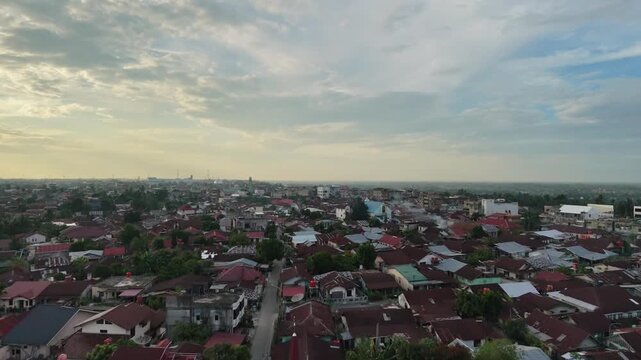 Aerial view of a small town settlement during sunset, with houses and buildings under a dramatic cloudy sky. Urban landscape, evening twilight, and community travel concept.