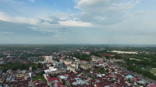Aerial view of a sprawling small town featuring dense residential houses and buildings under a bright daytime sky with clouds. Urban landscape, community, and travel concept.