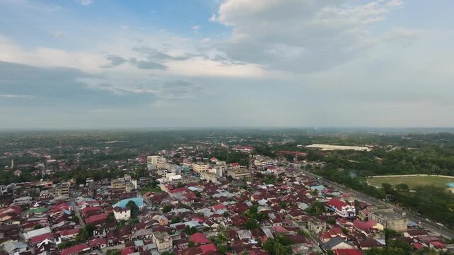 Aerial view of a sprawling small town featuring dense residential houses and buildings under a bright daytime sky with clouds. Urban landscape, community, and travel concept.